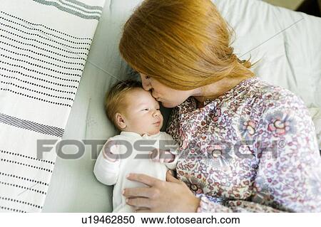 Stock Image - Woman kissing her newborn son's head. Fotosearch