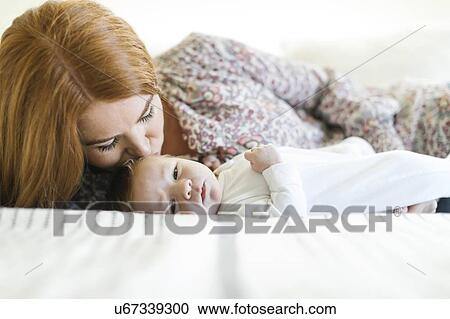 Stock Image - Woman kissing her newborn son's head. Fotosearch