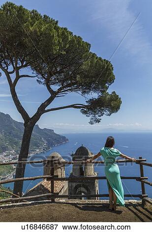 Stock Photo - Woman leaning on fence by church in Ravello, Italy. Fotosearch
