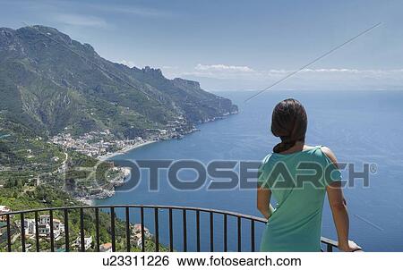 Stock Photograph - Woman leaning on railing by Amalfi Coast, Italy. Fotosearch