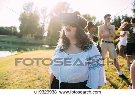 Stock Photo - Woman looking into VR headset in park. Fotosearch