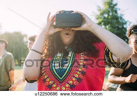Woman looking into VR headset in park View Large Photo Image Stock Photograph - Woman looking into VR headset in park. Fotosearch