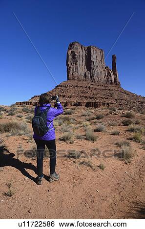 Stock Photograph - Woman photographing butte in Monument Valley, Arizona, USA. Fotosearch