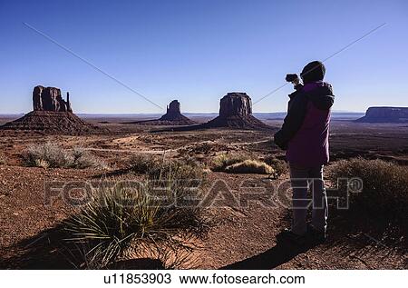 Stock Image - Woman photographing Monument Valley in Arizona, USA. Fotosearch