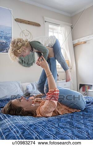Picture - Woman playing with her son on bed. Fotosearch