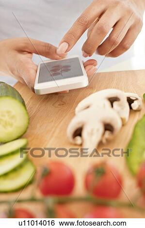 Woman preparing food using smartphone. View Large Photo Image Stock Photograph - Woman preparing food using smartphone.. Fotosearch