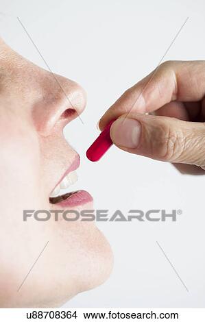 Woman putting a red pill in her mouth. View Large Photo Image Picture - Woman putting a red pill in her mouth.. Fotosearch