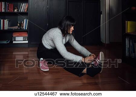 Woman putting on walking shoes on floor View Large Photo Image Stock Photo - Woman putting on walking shoes on floor. Fotosearch