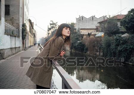 Stock Photo - Woman relaxing by river, Milano, Lombardia, Italy. Fotosearch