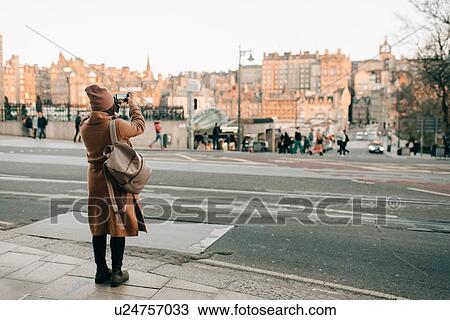 Stock Image - Woman sightseeing and taking photo, Calton Hill, Edinburgh, Scotland. Fotosearch