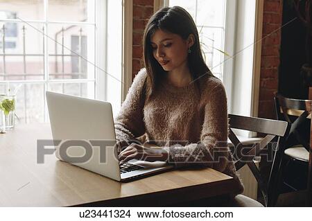 Woman sitting in restaurant with laptop View Large Photo Image Picture - Woman sitting in restaurant with laptop. Fotosearch
