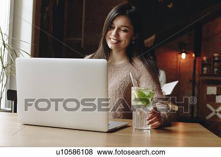 Stock Photo - Woman sitting in restaurant with laptop. Fotosearch