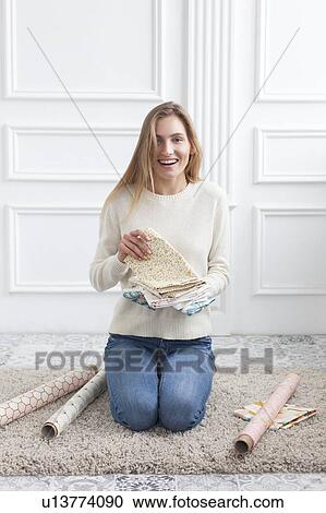 Stock Image - Woman sitting on rug with variety of fabrics. Fotosearch