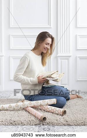 Stock Image - Woman sitting on rug with variety of fabrics. Fotosearch