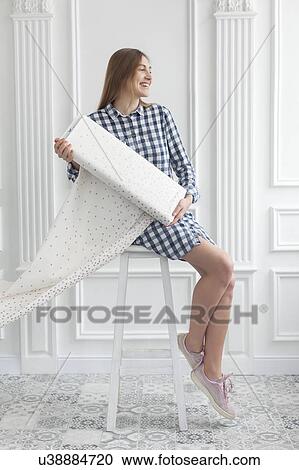 Woman sitting on stool unrolls fabric View Large Photo Image Stock Image - Woman sitting on stool unrolls fabric. Fotosearch