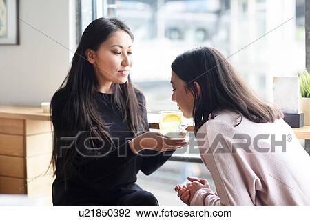 Woman smelling glass of lemon juice held by friend View Large Photo Image Stock Image - Woman smelling glass of lemon juice held by friend. Fotosearch