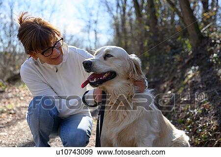 Stock Photo - Woman taking pet dog for walk in park. Fotosearch