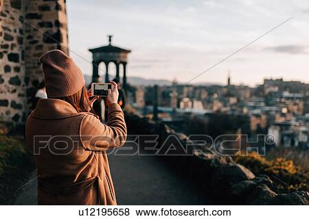 Stock Photo - Woman taking photo from Calton Hill, Edinburgh, Scotland. Fotosearch
