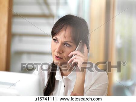 Stock Image - Woman talking through a business issue over the phone. Fotosearch