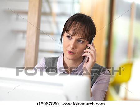 Stock Image - Woman talking through a business issue over the phone. Fotosearch