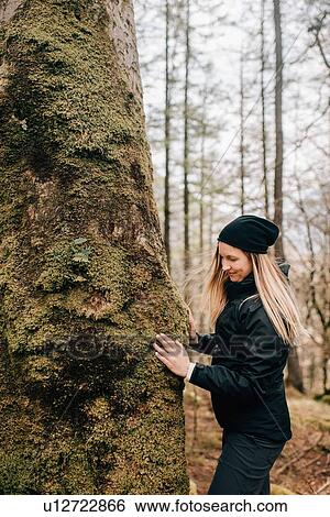 Stock Photograph - Woman touching tree, Trossachs National Park, Canada. Fotosearch