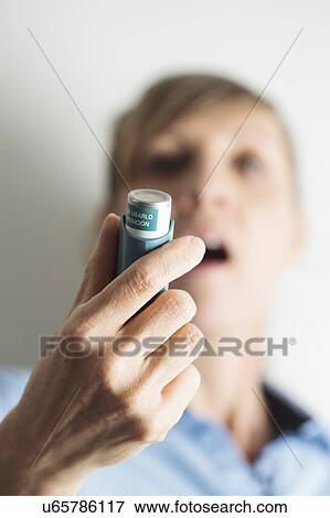 Woman using an inhaler to treat an asthma attack. The inhaler contains bronchodilator drugs, which widen constricted airways in the lungs. View Large Photo Image Stock Photo - Woman using an inhaler to treat an asthma attack. The inhaler contains bronchodilator drugs, which widen constricted airways in the lungs.. Fotosearch