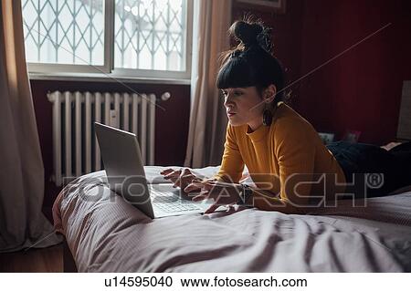 Woman using laptop on bed View Large Photo Image Stock Image - Woman using laptop on bed. Fotosearch