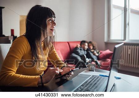 Woman using smartphone, friends relaxing in background in home office View Large Photo Image Stock Image - Woman using smartphone, friends relaxing in background in home office. Fotosearch