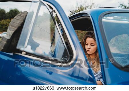 Stock Image - Woman using smartphone inside car. Fotosearch