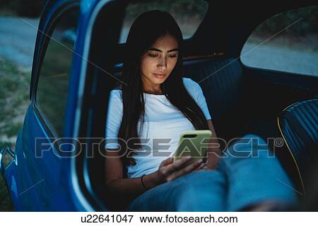 Stock Photo - Woman using smartphone inside car. Fotosearch
