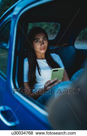 Stock Photo - Woman using smartphone inside car. Fotosearch