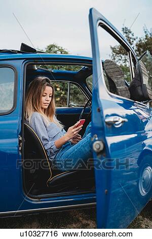 Woman using smartphone inside car View Large Photo Image Stock Photograph - Woman using smartphone inside car. Fotosearch