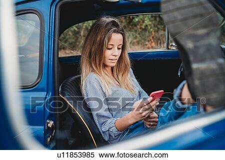 Woman using smartphone inside car View Large Photo Image Stock Photography - Woman using smartphone inside car. Fotosearch
