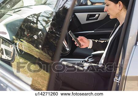 Woman using smartphone inside vehicle View Large Photo Image Stock Image - Woman using smartphone inside vehicle. Fotosearch