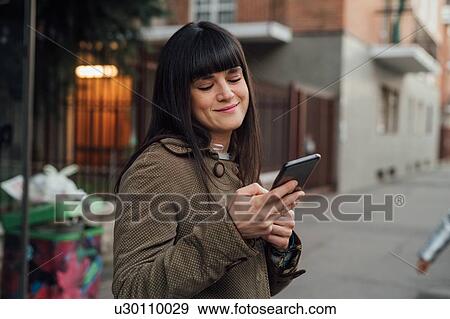 Woman using smartphone on pavement, Milano, Lombardia, Italy View Large Photo Image Stock Photo - Woman using smartphone on pavement, Milano, Lombardia, Italy. Fotosearch