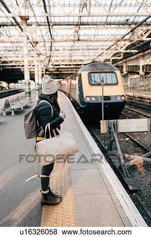 Stock Photo - Woman waiting on platform in train station, Edinburgh, Scotland. Fotosearch