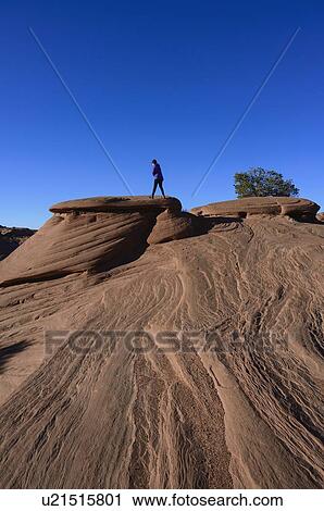 Stock Image - Woman walking on smooth rocks in Monument Valley, Arizona, USA. Fotosearch