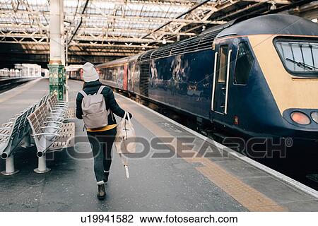 Stock Image - Woman walking to train at platform, Edinburgh, Scotland. Fotosearch