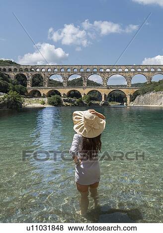 Woman wearing hat standing in Gardon River by Pont du Gard in Vers-Pont-du-Gard, France View Large Photo Image Stock Photo - Woman wearing hat standing in Gardon River by Pont du Gard in Vers-Pont-du-Gard, France. Fotosearch