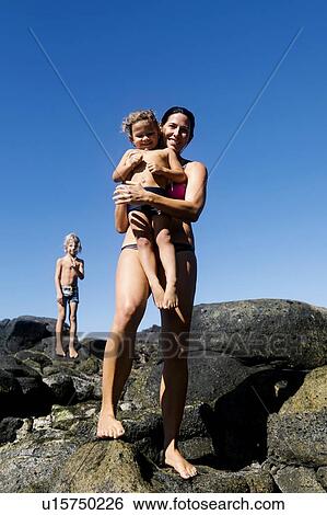 Woman with her sons on rocks at beach View Large Photo Image Stock Photograph - Woman with her sons on rocks at beach. Fotosearch