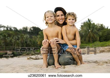 Woman with her sons sitting on her lap on beach View Large Photo Image Stock Image - Woman with her sons sitting on her lap on beach. Fotosearch