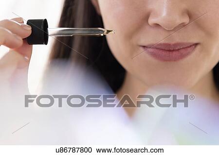Stock Image - Woman with pipette of essential oil. Fotosearch