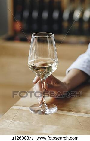 Stock Photo - Woman's hand holding glass of white wine. Fotosearch