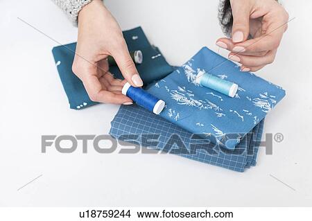 Woman's hand matching thread to blue fabric View Large Photo Image Picture - Woman's hand matching thread to blue fabric. Fotosearch