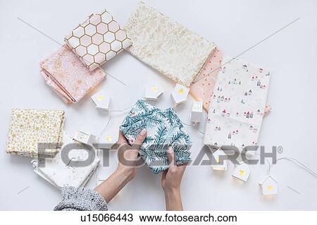 Stock Image - Woman's hands holding fabric with pine frond print. Fotosearch