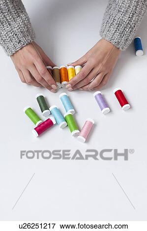 Stock Photo - Woman's hands organizing colorful spools of thread. Fotosearch