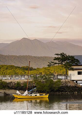 Stock Photo - Yellow sailboat on beach at sunset in Port Douglas, Australia. Fotosearch