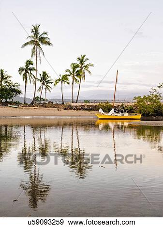Stock Photo - Yellow sailboat on beach in Port Douglas, Australia. Fotosearch