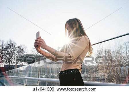 Young blond woman outside sunlit office building taking smartphone selfie, Turin, Piemonte, Italy View Large Photo Image Stock Photo - Young blond woman outside sunlit office building taking smartphone selfie, Turin, Piemonte, Italy. Fotosearch