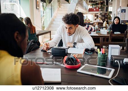 Stock Photo - Young businessman and woman remote working at cafe table. Fotosearch